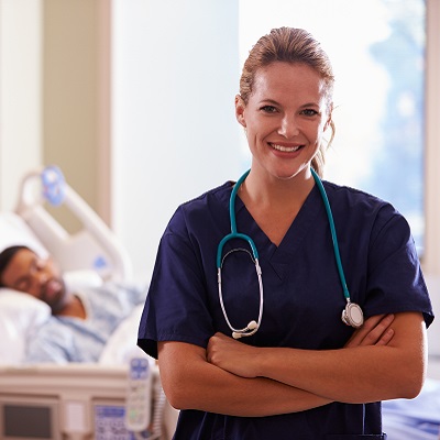 A white nurse with black patient in  background.